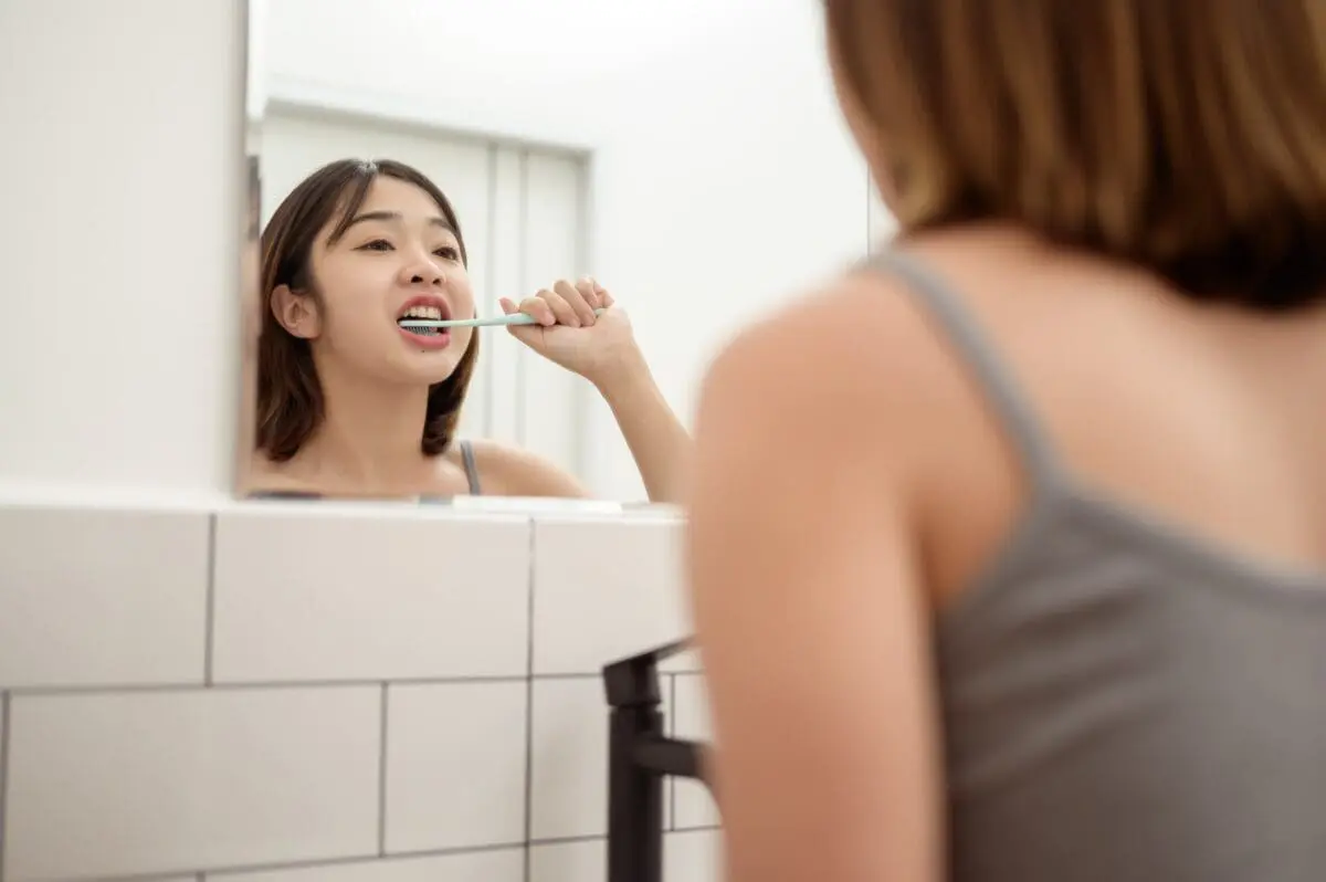 A young woman brushing her teeth in restroom