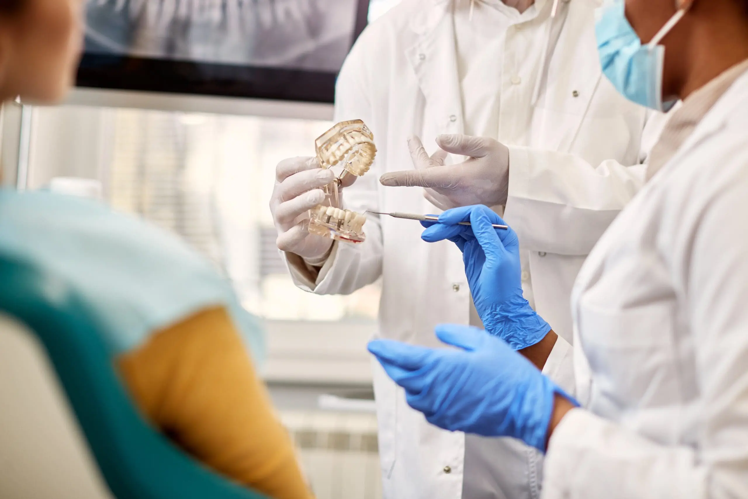Close up of orthodontists using dental model during dental appointment with a patient.