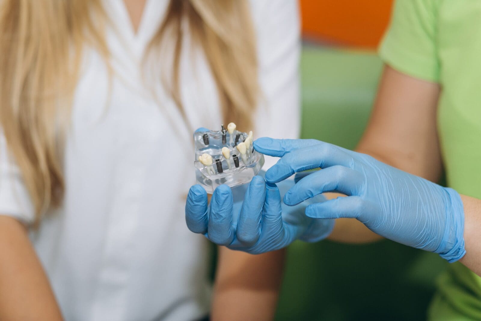 The dentist conducts teaching for the patient and shows the implant in the dental clinic.